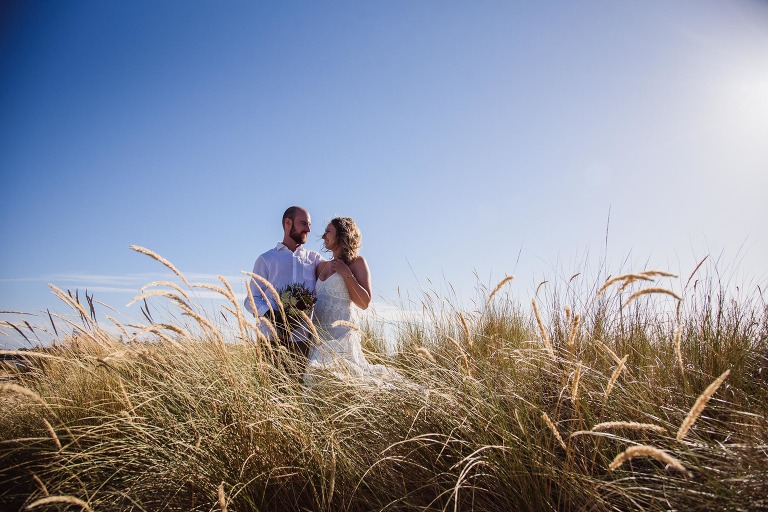 bride and groom relaxing in the dunes at their Bunbury barefoot beach wedding